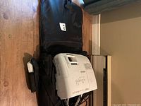 Projector and black carrying case on hardwood floor, with cables partially visible