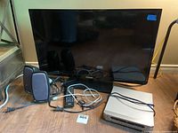 Toshiba 32-inch TV 32L110U with remote, Daytek DVD player, black power bar, remote, and Creative speakers on floor