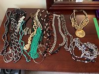 Photo showing various costume jewelry necklaces arranged on a flat surface including multiple styles of beads and chains.