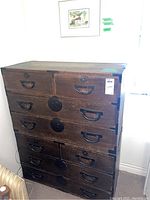Front view of the two-piece wooden dresser showing multiple drawers and metal circular decorative accents with wear and scratches.