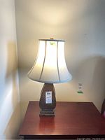 Pair of lamps on a wooden table against a wall, with cream fabric shades and curved carved wooden bases.