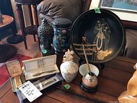 Overview of all items on table showing the Dunhill lighter, pens, mate pot, stone Buddha, trinket box and decorative tray