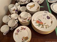 Full view of the Royal Worcester Eversham dinnerware set including plates, bowls, cups, saucers, and serving pieces arranged on a table.