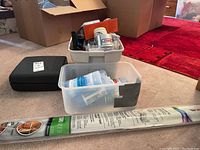 Overall contents showing two plastic bins with various items including the black drill case, hardware, and accessories.