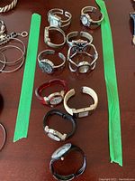 Top-down photo showing ten women's watches arranged vertically in two columns, with a variety of band and face styles in silver tones, black, cream, and red bands.