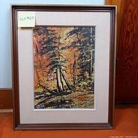 Framed oil painting showing a forest landscape with tree trunks and foliage in warm orange tones.