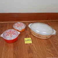 All three casserole dishes shown together on floor: large beige oval dish and two small round dishes (orange and red)