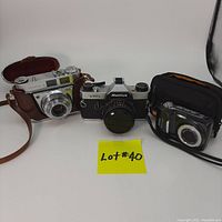 Centered image showing all three cameras together with 'Lot #40' label: Mamiya NC1000s SLR in center, Kodak Retinette 1A with brown leather case on left, Kodak Easyshare digital camera with case on right.