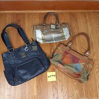 Photo shows three leather purses laid out on wooden floor including navy blue, tan with metallic accents, and multicolor patchwork designs.