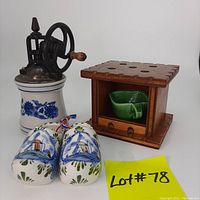 Photo of a lot including two blue and white miniature Dutch ceramic shoes, a blue and white ceramic coffee grinder with metal handle, and a wooden miniature foot warmer containing two small green ceramic cups.