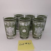 Photo of six vintage green commemorative glasses celebrating the Canadian Centennial 1867-1967 with Canadian coats of arms and provincial crests in white print.