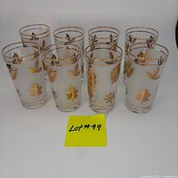 Eight vintage frosted highball glasses decorated with gold leaf designs and gold rims on a white surface, showing the set included in the lot.