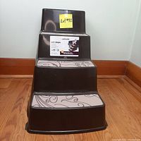 Front view of dark brown Petmate pet steps showing three stairs with light patterned carpet tread covering each step.