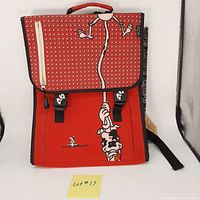 Front of red backpack showing dog graphic on flap and pocket, with two buckle closures and top handle.