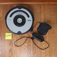 Top-down view of Roomba Pet Series 563 robot vacuum with charging dock and power adapter on wooden floor.