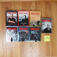 Photo of seven DVD box sets for The Sopranos TV series arranged on a wooden floor, covering all six seasons.