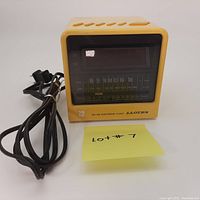 Front view of the vintage Lloyd's light yellow cube electronic clock and AM/FM radio with display and radio dial, power cord included.