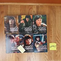 Photo showing six DVD box sets of Xena Warrior Princess, Seasons One through Six, arranged on a wooden floor. Season Five has a sticky note mentioning a missing disc.