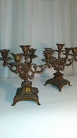 Photo of both antique metal candelabras showing overall size, shape, and design features.