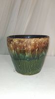 Full view of glazed antique pottery plant pot displaying overall sunburst glaze design in browns and greens.