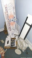 Photo showing the main matt cutter unit, packaging box, and assorted parts on the floor near a chair.