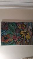 Full view of the large floral painting on stretched canvas showing colorful flowers in warm tones.