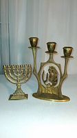 Shows both brass candle holders side by side, highlighting size difference and detail