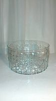 Front view of clear glass bowl showing floral embossed design along the sides.