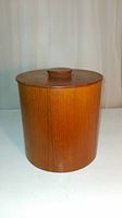 Front view of closed vintage teak wood cookie canister showing smooth cylindrical shape and lid