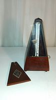 Wooden metronome with cover removed, showing the full front and internal scale with pendulum arm visible