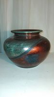 Front view of raku vase showing metallic copper and green crackled glaze divided by curved line.