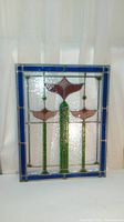 Full view of handmade stained glass window panel showing blue border and flower design