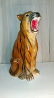 Side angle view of the large chalkware tiger bank showing orange and black stripes and open mouth with red tongue.