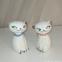 Front view of both vintage ceramic cat salt and pepper shakers showing their facial details and colored collars.