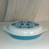Full view of vintage blue Pyrex divided casserole with white lid featuring blue floral design.
