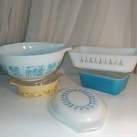 Photo showing 7 Pyrex pieces: 2 mixing bowls, one with Amish pattern, yellow casserole, blue butter dish, casserole with garland design, loaf pan, and floral lid.