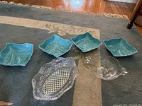 Four turquoise ceramic serving dishes and one clear pressed glass serving dish.