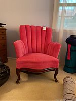 Front view of hot pink plush upholstered armchair with channel back and wooden legs.