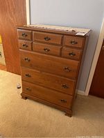 Full frontal view of the solid wood dresser showing four large drawers and three smaller drawer fronts at the top with brass handles.