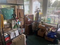 Tall and short black metal shelving units visible behind various boxes and stored items. Shelving units have grid wire shelves and black metal framing.