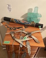 Art pieces including boomerang, didgeridoo, glass Inukshuk, and metal wall hanging displayed on wooden furniture.