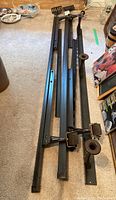 View of metal bed frame lying on carpet showing multiple horizontal metal bars and attached wheels for mobility.