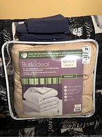 Queen size bamboo rayon covered down duvet in beige color in its original plastic packaging with label showing specifications and measurements.