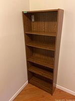 Front view of the laminate bookshelf showing four shelves and woodgrain finish