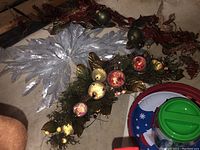 Photo of silver glitter poinsettia leaves and Christmas swag with ornaments and gold leaves on floor