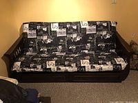 Front view of futon showing wooden arms, printed mattress and closed drawers