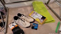 Lot contents with white Footjoy golf shoes, unopened package of black SpringYard ThermaSox heated socks, a small box for a scarf hanger, and green exercise mat.