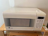 Front view of white GE microwave with keypad and digital display.