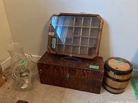 Photo including glass oil lamp, wood box with glass lid placed on top of larger wood box, and wood barrel