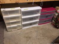 Three plastic organizer units with drawers, showing locations and different sizes, some with markings and visible signs of wear.